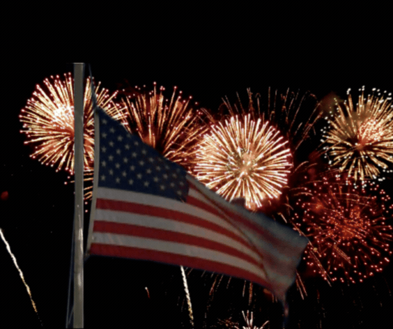 An American flag waving in front of fireworks